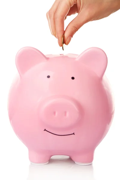 Female hand putting coin into piggy bank isolated on white — Stock Photo, Image