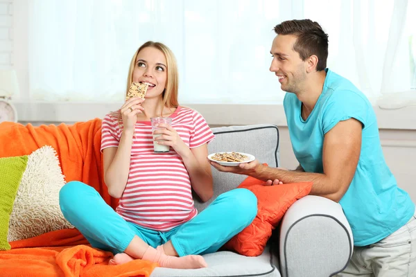 Pregnant woman with husband on sofa — Stock Photo, Image