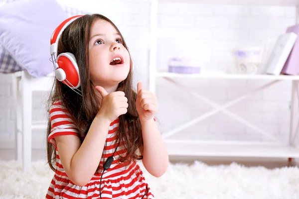 Beautiful little girl listening to music in room — Stock Photo, Image