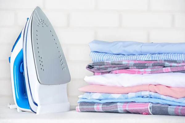 Electronic ironing and pile of clothes — Stock Photo, Image