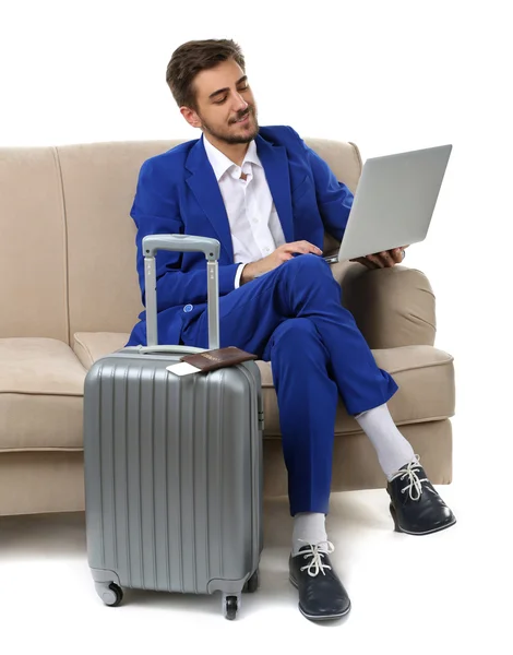 Homem de negócios com mala e laptop sentado no sofá isolado em branco — Fotografia de Stock