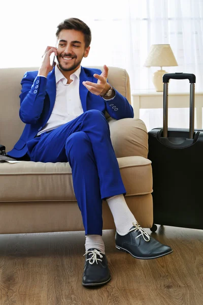 Business man with suitcase sitting on sofa at home — Stock Photo, Image