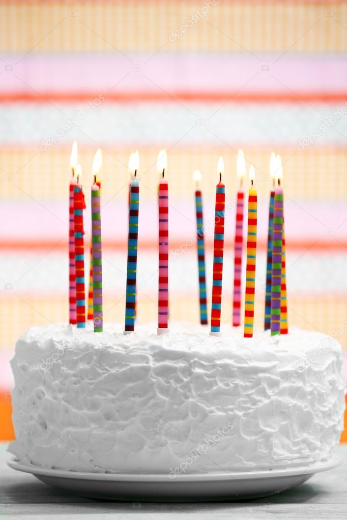 Birthday cake with candles on colorful striped background