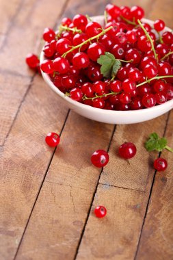 Ahşap masa üzerinde kase taze kırmızı kuş üzümü yakın çekim