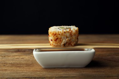 Sosu ve ahşap sopa ile koyu arka plan üzerinde rulo