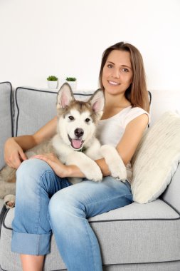 Malamute köpeğini odasında kanepede oturan kadın