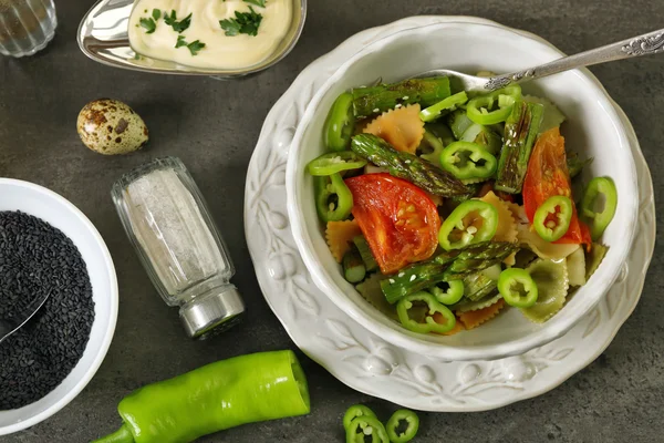 Roasted asparagus and tasty colorful pasta with vegetables, spices in bowl on colorful background — Stock Photo, Image