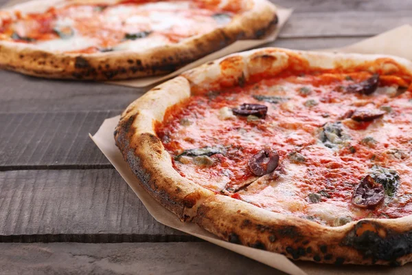 Deliciosas pizzas na mesa de madeira, close-up — Fotografia de Stock