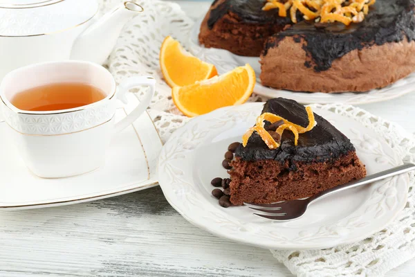 Торт з шоколадною глазур'ю та апельсином на тарілці, на дерев'яному фоні — стокове фото