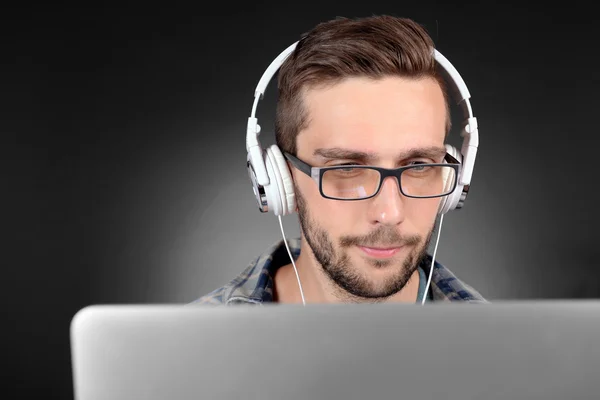 Joven guapo con portátil sobre fondo gris — Foto de Stock