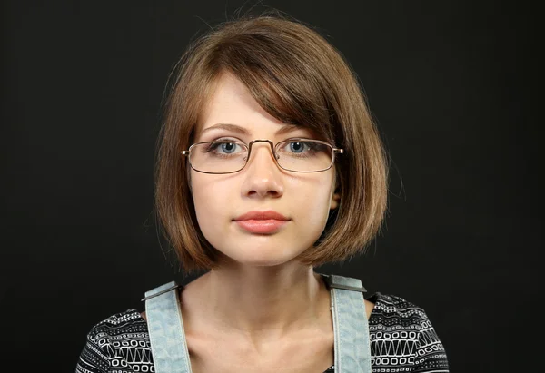 Atraktivní mladá žena s brýlemi na šedém pozadí — Stock fotografie