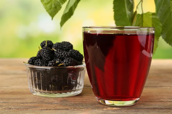 Glass of refreshing mulberry juice with berries on bright background — Stock Photo, Image