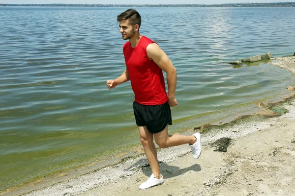 Ung man joggar på stranden — Stockfoto