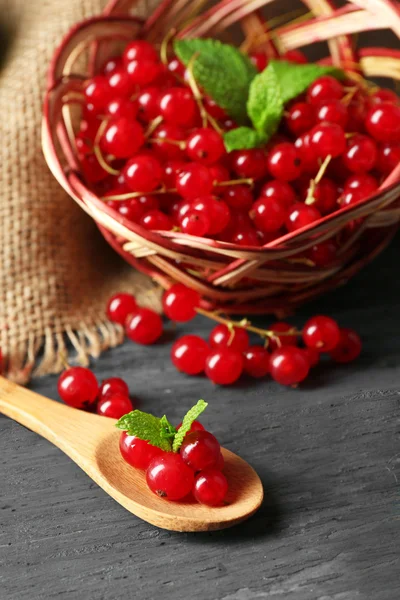 Ripe red currant in wicker basket on wooden background — Stock Photo, Image