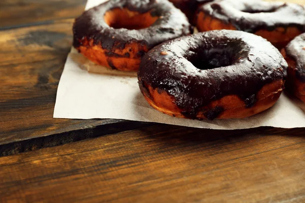 Delicious doughnuts with chocolate icing on table close up — Stock Photo, Image
