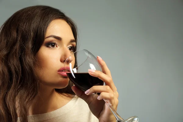 Porträt einer jungen Frau mit einem Glas Rotwein auf grauem Hintergrund — Stockfoto