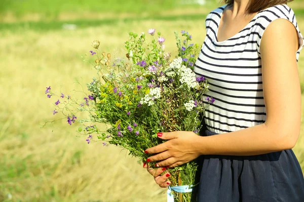 Mãos femininas com buquê de flores silvestres — Fotografia de Stock