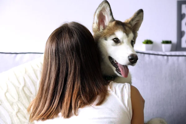 Vrouw knuffelen malamute hond op kamer — Stockfoto