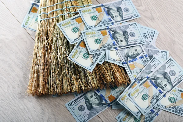 Dólares e vassoura no chão de madeira, close-up — Fotografia de Stock