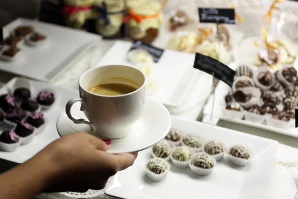 Vrouwelijke hand met kopje koffie op tabelachtergrond — Stockfoto