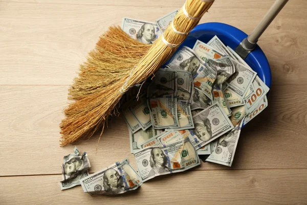Broom sweeps dollars in garbage scoop