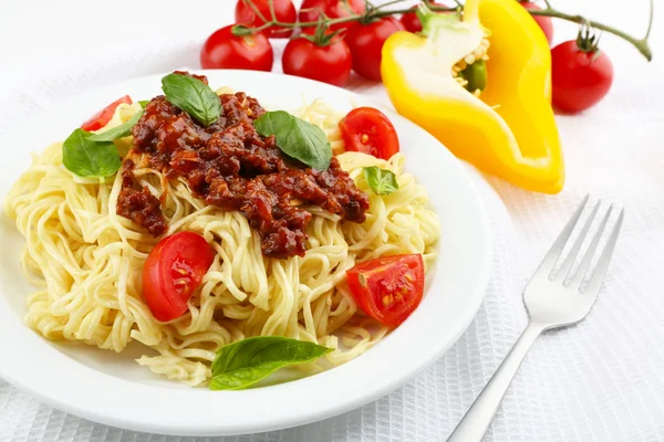 Spaghetti alla bolognese su piatto bianco, su fondo di legno a colori — Foto Stock