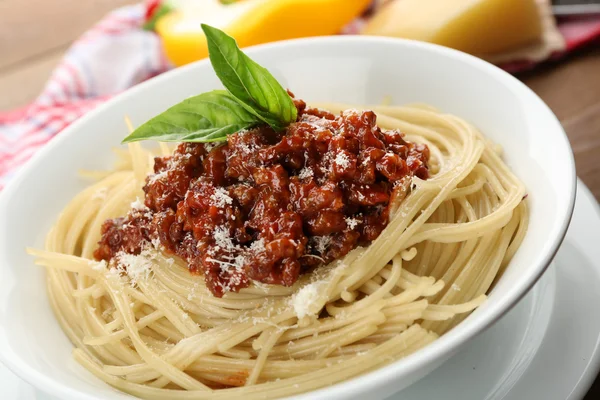Spaghetti Bolognese with parmesan cheese in white bowl, on color wooden background — Stock Photo, Image