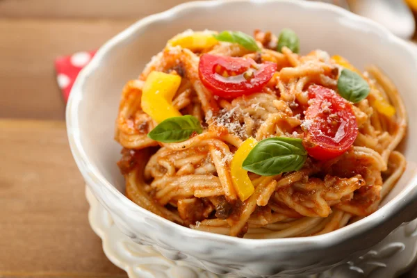 Spaghetti fatti in casa alla bolognese con parmigiano in ciotola bianca, su fondo di legno a colori — Foto Stock