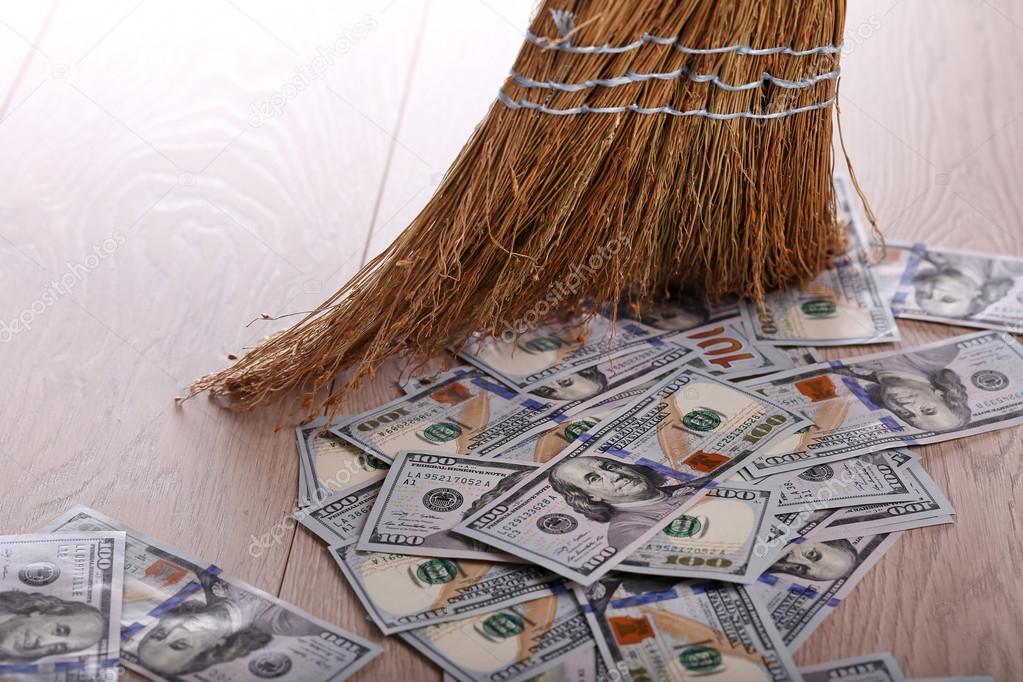 Dollars and broom on wooden floor, closeup