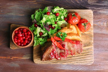 sığır eti ile kızılcık sosu, ahşap arka plan üzerinde kesme tahtası kavrulmuş patates dilimleri