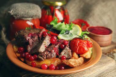 kızılcık sosu, salata ve ahşap arka plan üzerinde plaka üzerinde kavrulmuş sebze ile lezzetli kavrulmuş et