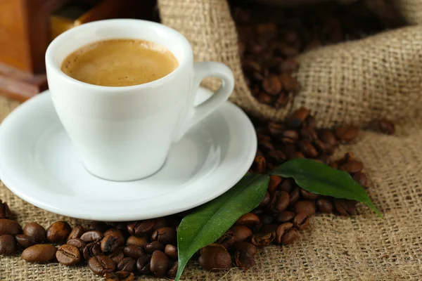 Xícara de café com grãos na mesa de perto — Fotografia de Stock