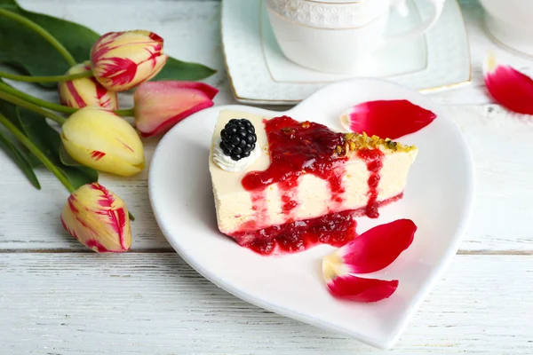 Tasty piece of cheesecake with berry sauce on plate on table close up — Stock Photo, Image