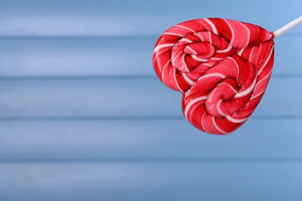 लकड़ी की पृष्ठभूमि पर दिल के आकार में उज्ज्वल lollipop — स्टॉक फ़ोटो, इमेज