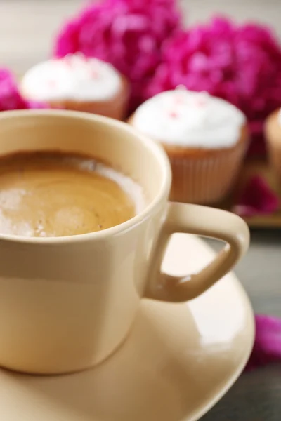 Composizione con tazza di caffè, muffin e fiori di peonia su fondo di legno — Foto Stock