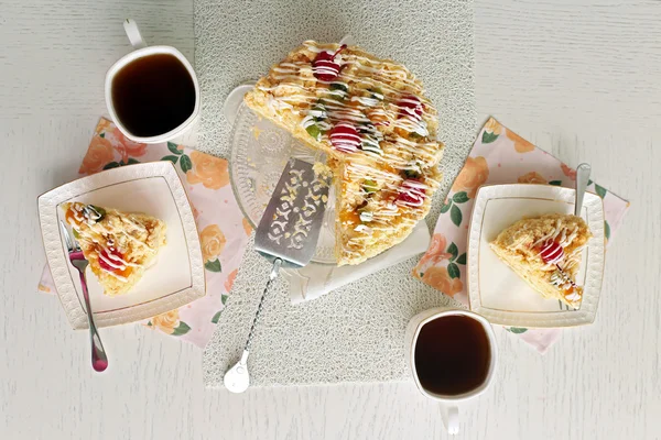 Pokoju, smaczne ciasto masło na talerzu, kubki herbaty na kolor drewniane tła — Zdjęcie stockowe