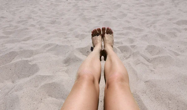 Pernas femininas no fundo de areia — Fotografia de Stock