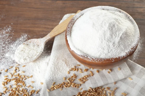 Whole flour with wheat on wooden table, closeup — Stock Photo, Image