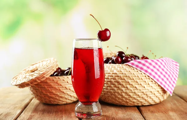 Glass of cherry juice on wooden table on light blurred background — Stock Photo, Image