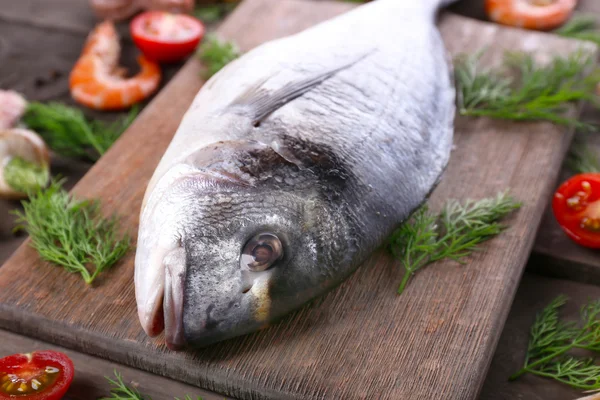 Рыба Дорадо и другие ингредиенты на деревянном столе, крупным планом — стоковое фото