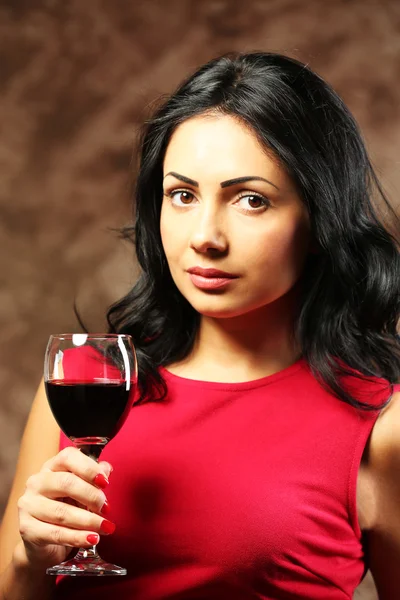 Hübsche junge Frau mit Weinglas auf braunem Hintergrund — Stockfoto