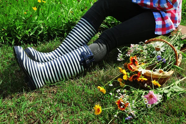 Femme en bottes en caoutchouc assis sur la prairie — Photo