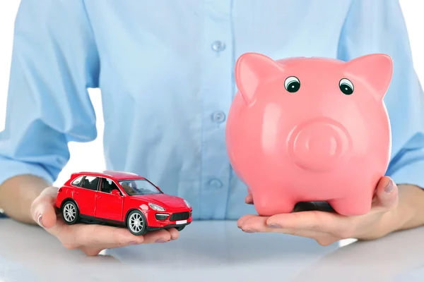 Hands holding piggy bank and model of car — Stock Photo, Image