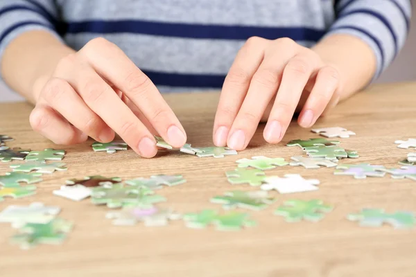 Female hands assembling puzzle — Stock Photo, Image