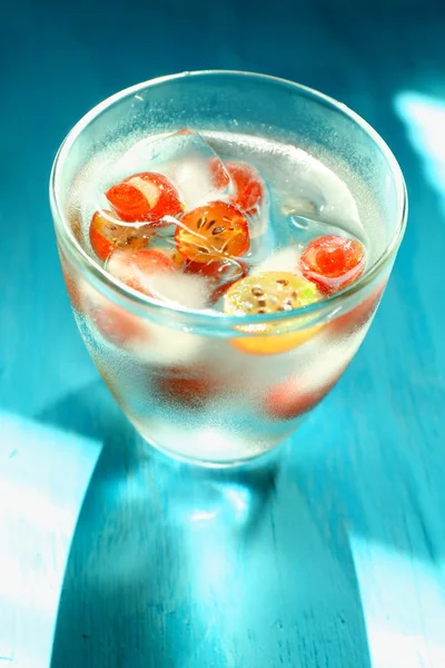 Glas kaltes erfrischendes Sommergetränk mit Beeren und Eiswürfeln auf dem Tisch in Großaufnahme — Stockfoto