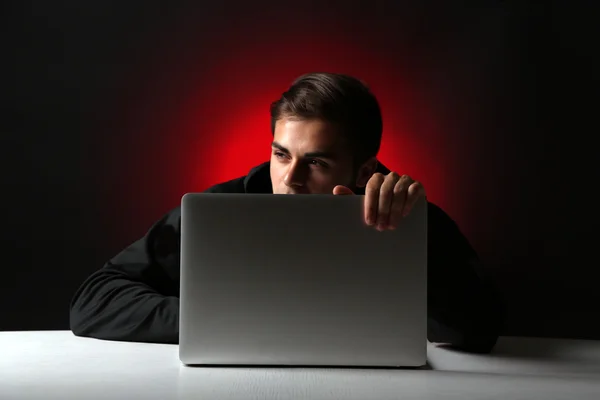 コンピューターとカラフルな暗い背景上のラップトップを持つハッカー — ストック写真