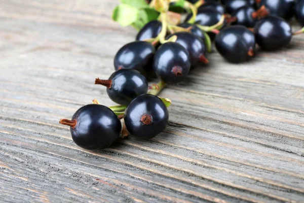 Högen av svarta vinbär på träbord, närbild — Stockfoto