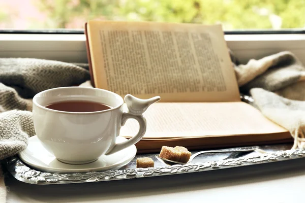 Xícara de chá com livro sobre bandeja de metal, close-up — Fotografia de Stock