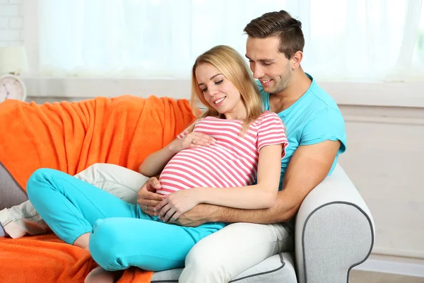 Pregnant woman with husband on sofa — Stock Photo, Image