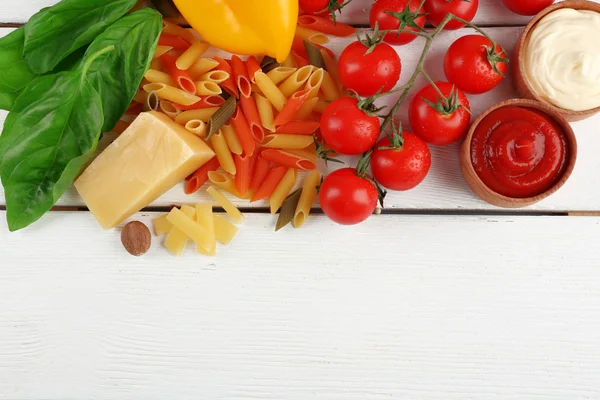 Pasta penne con pomodori, formaggio e basilico su sfondo di legno di colore — Foto Stock